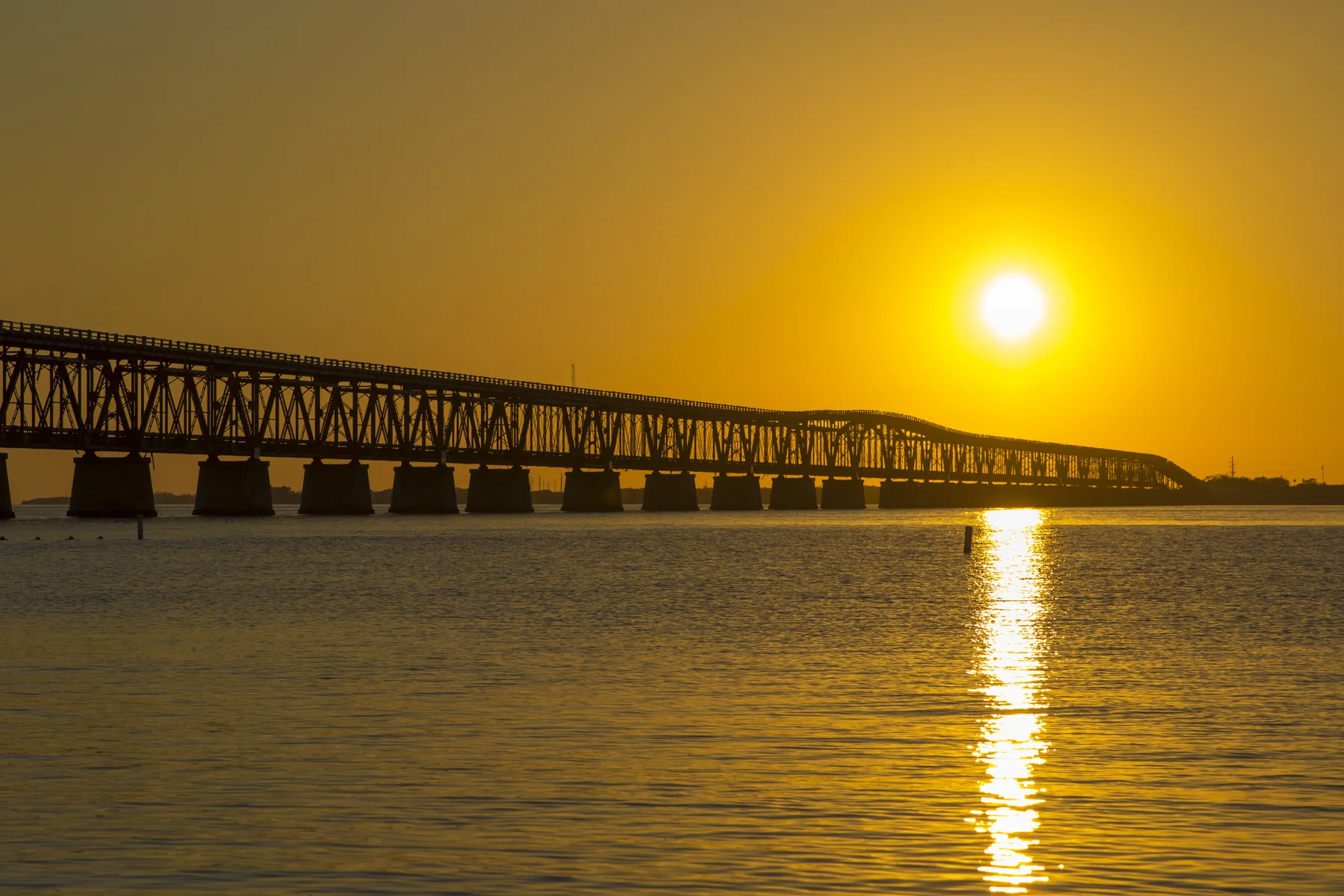 Historic Bahia Honda Rail Bridge silhouetted against a brilliant golden sunset over the water