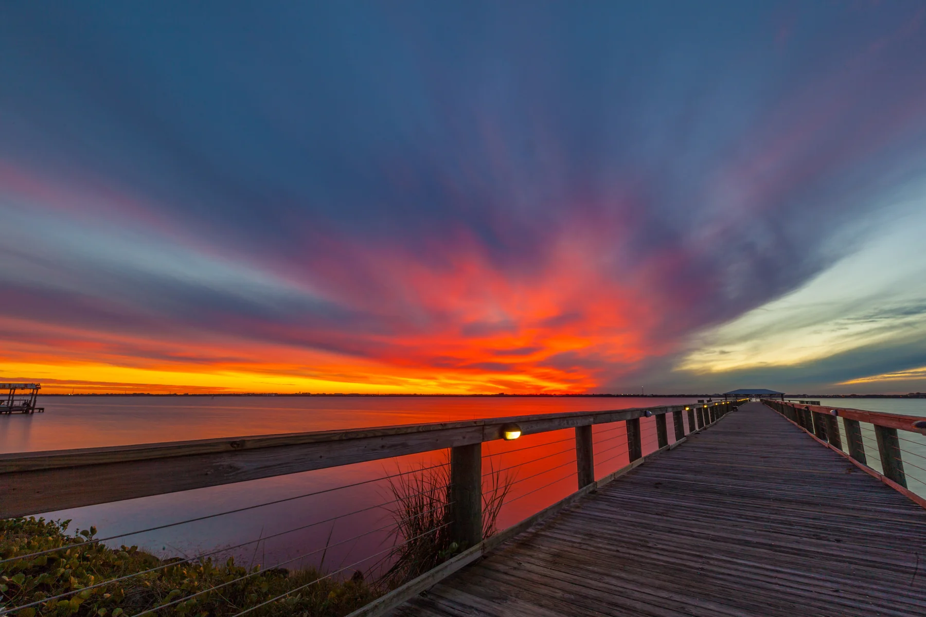 Dramatic sunset over a Brevard County pier, sky ablaze with red and orange over the Indian River